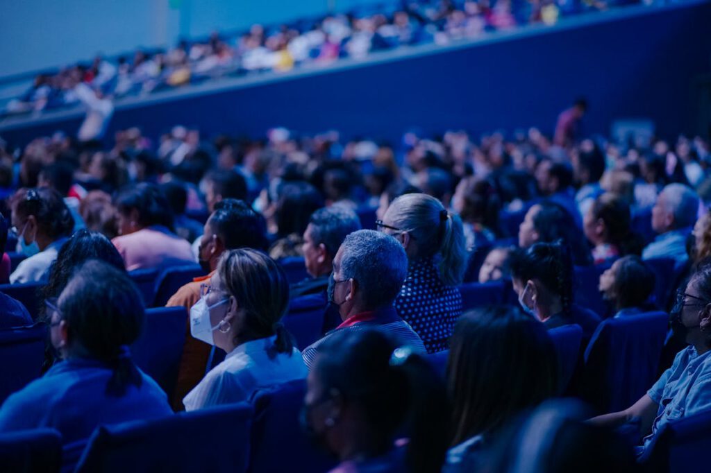 Diverse audience sitting in rows, attending an indoor conference or event.